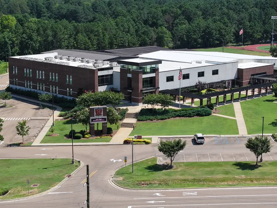 Wide aerial view of a subdivision and commercial buildings under blue sky